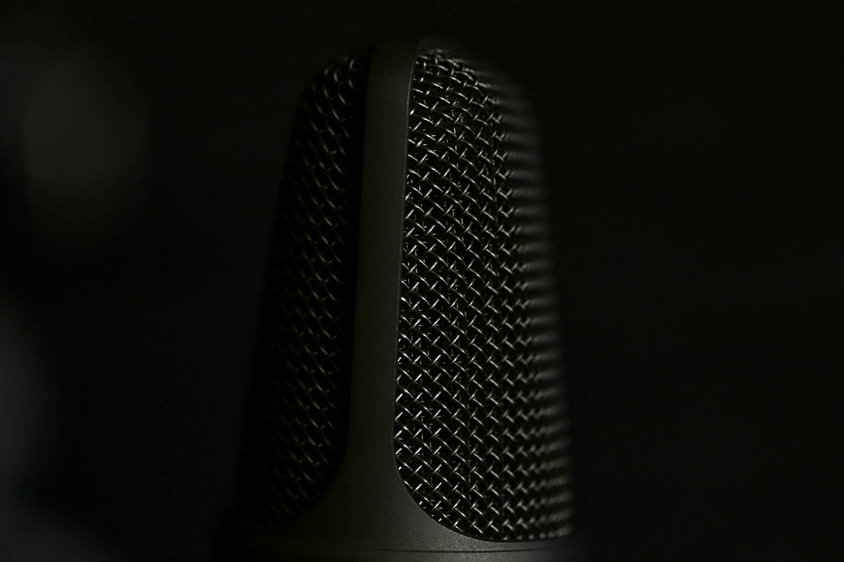 暗色背景中一支錄音室麥克風的金屬網罩特寫，象徵語音輸入。